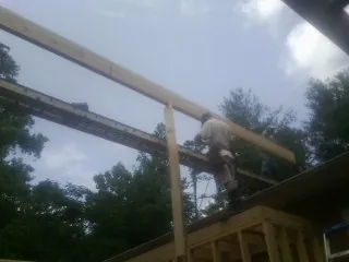 Carpenter setting a ridge beam over a new addition frame — Ice Dam Removal by Roofing Brothers in Jersey Shore