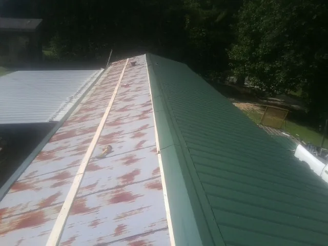 Old rusted panels beside newly installed green metal roofing — Wind Damage Roof Repair by Roofing Brothers in Jersey Shore