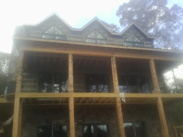 Dormers and porch framing on a large log home under construction — Roof Coating work by our crew in Jersey Shore