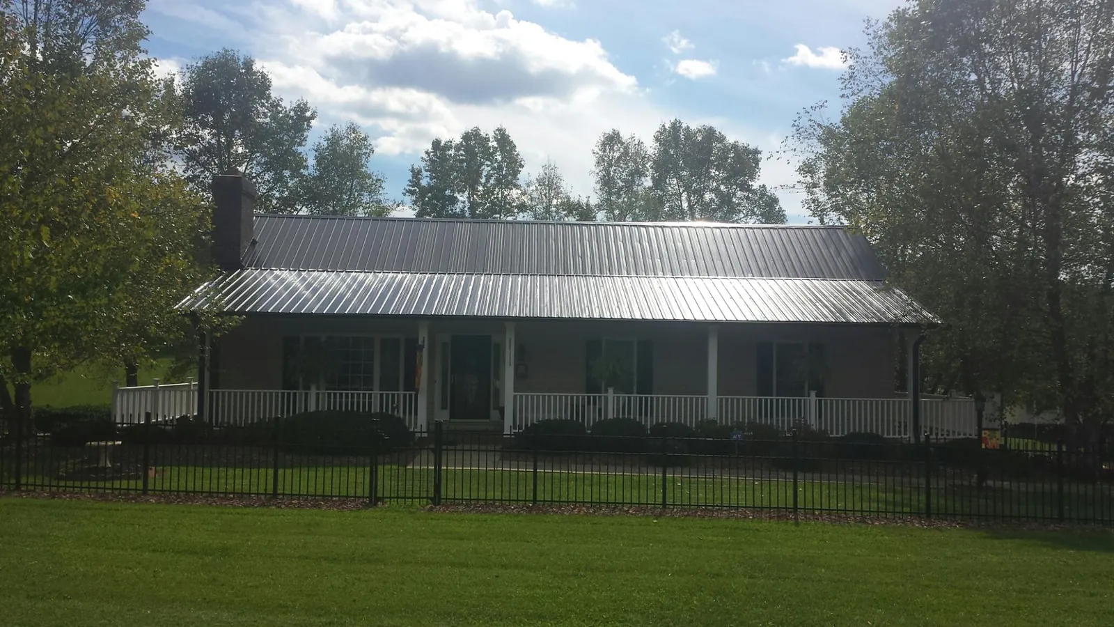 Gray metal roof on a brick ranch with a full width front porch — Gutter Guard Installation work by our crew in Jersey Shore