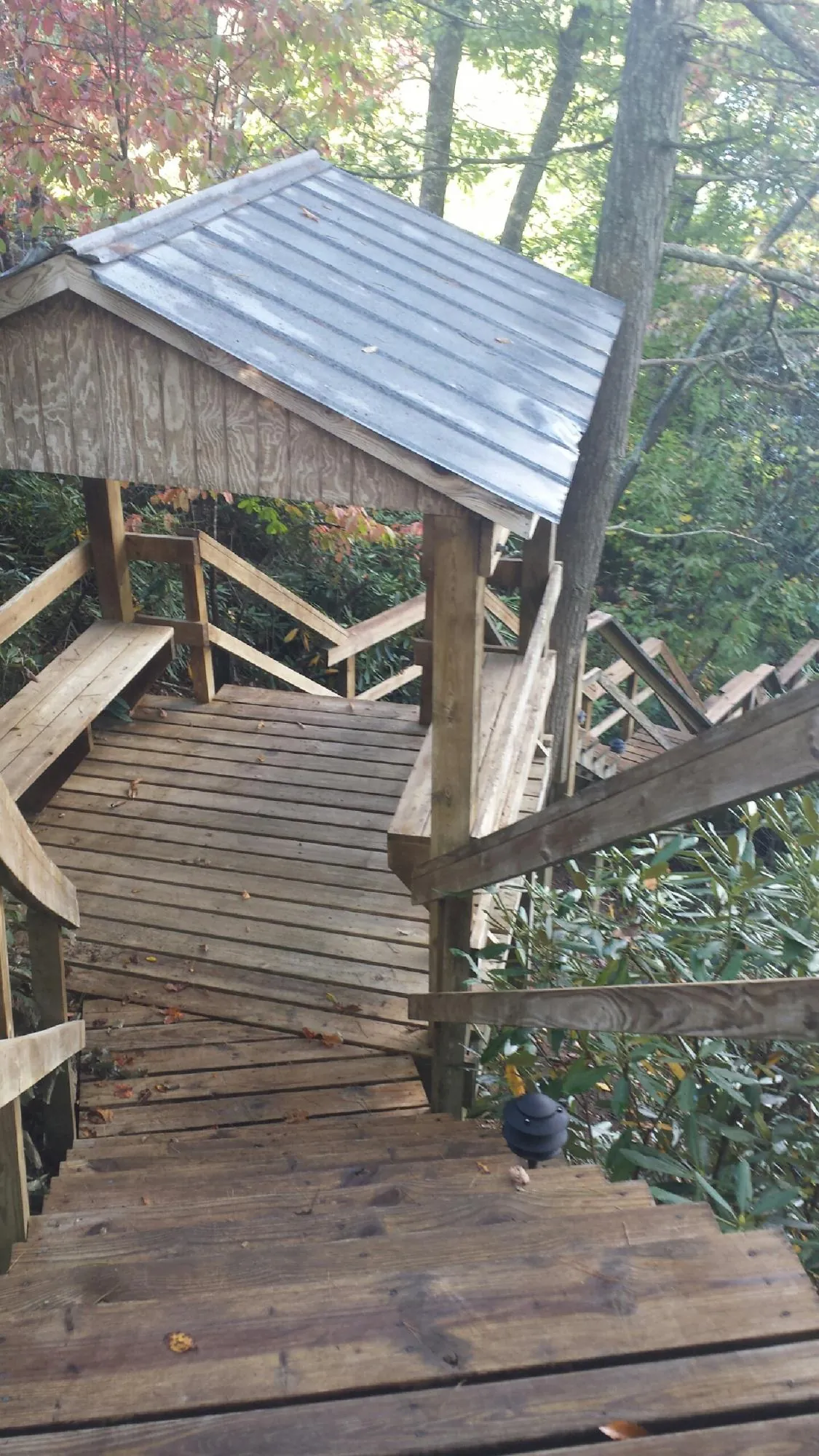 Metal roofed shelter over wooden steps on a wooded walkway — Skylight Repair & Installation work by our crew in Jersey Shore