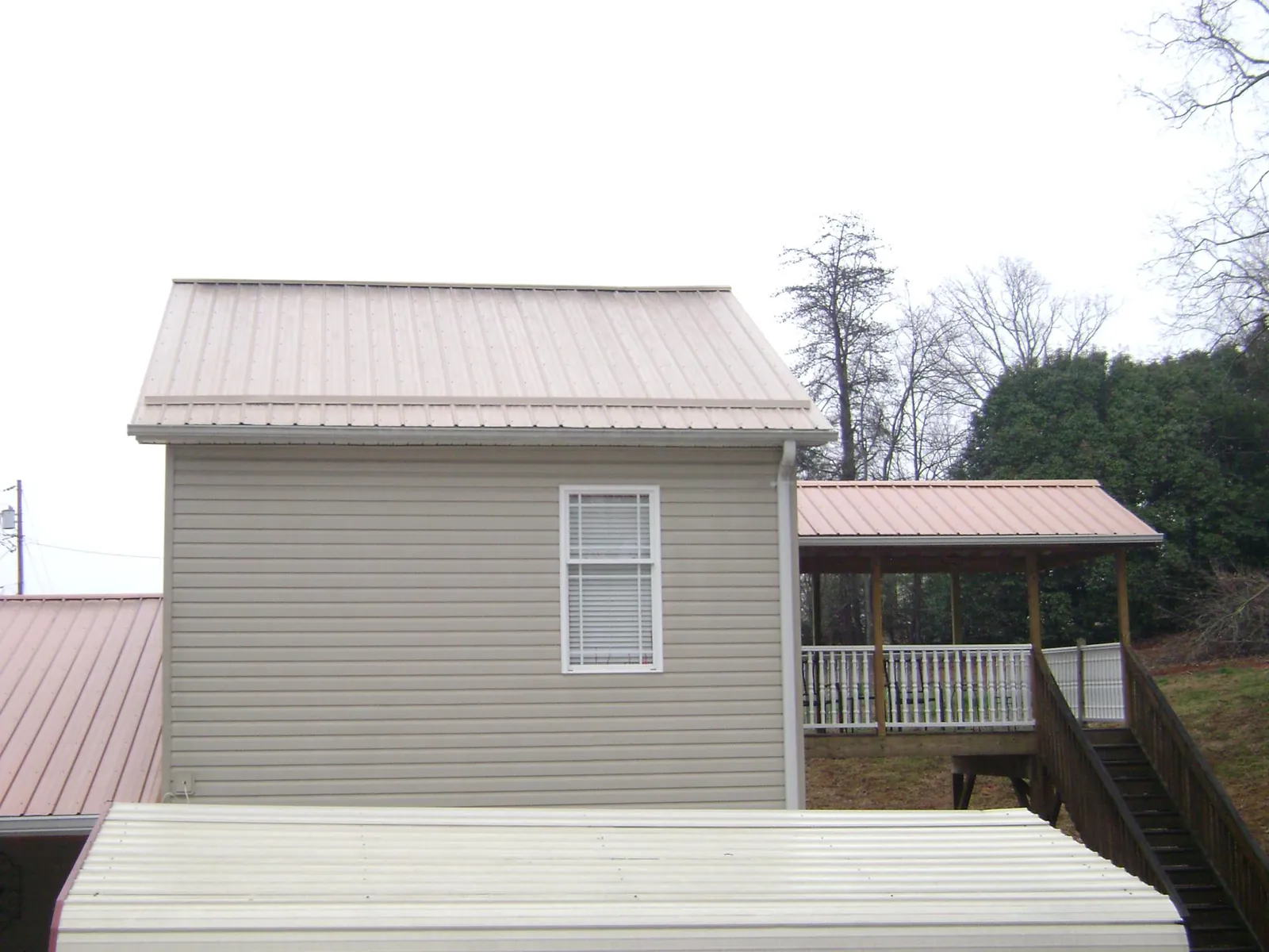 Tan metal roofs on a two story addition and attached porch, from a Roof Replacement job in Jersey Shore
