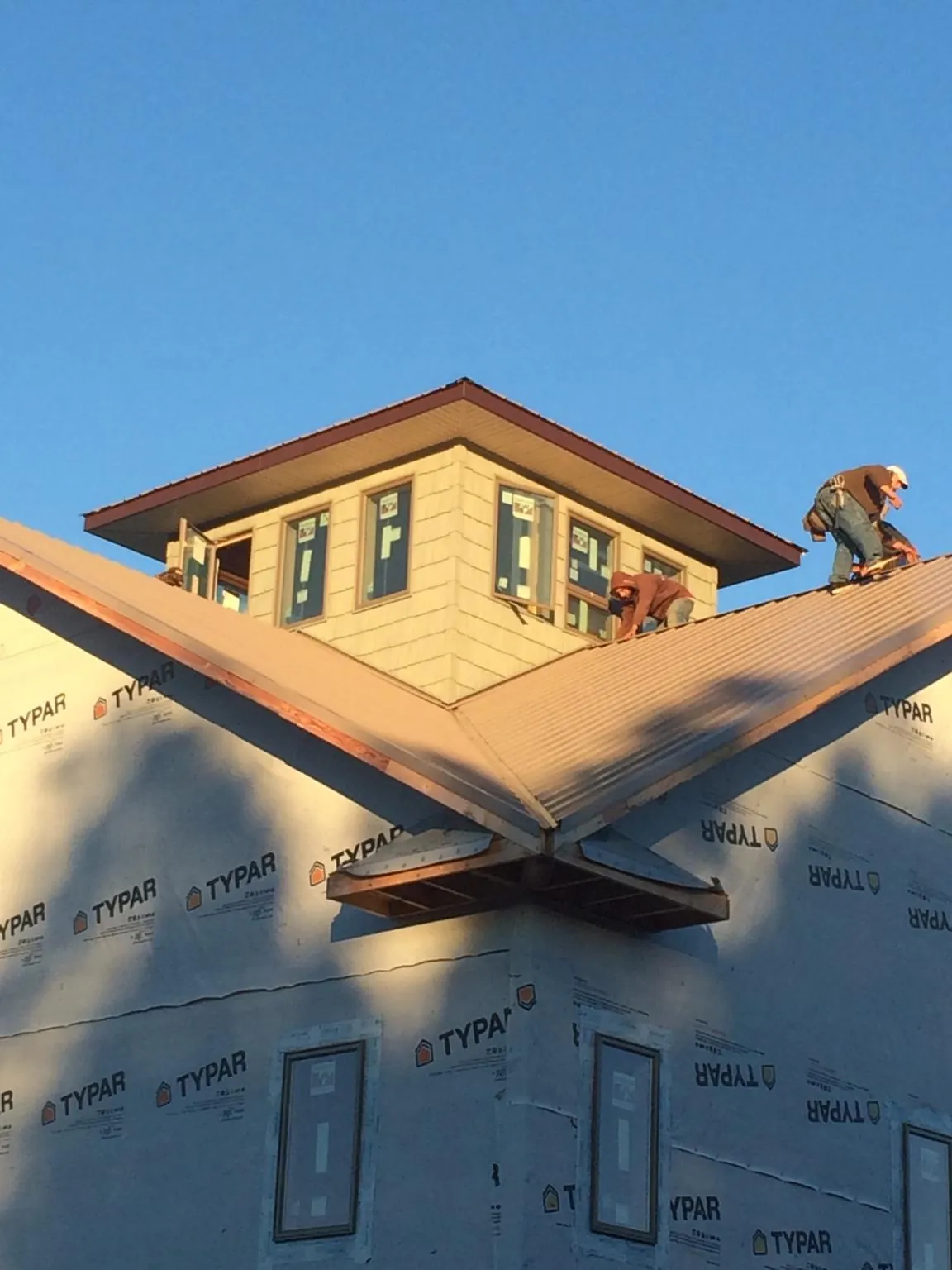 Roofers working around a rooftop cupola on a new metal roof at sunset — Roof Waterproofing in Jersey Shore by Roofing Brothers